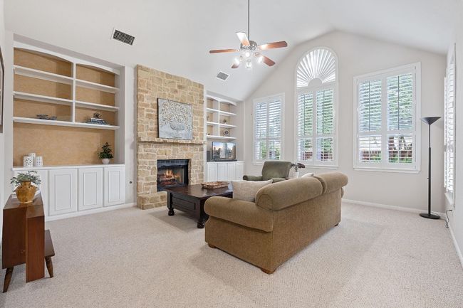 Carpeted living area with plenty of natural light, ceiling fan, built in features, and vaulted ceiling | Image 4