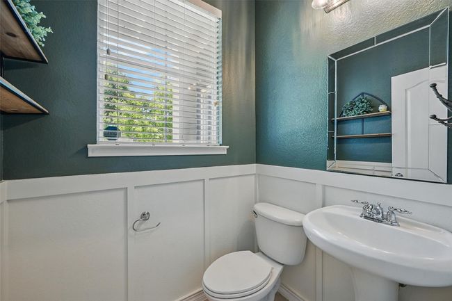 Bathroom with a decorative wall, toilet, a textured wall, a sink, and wainscoting | Image 21