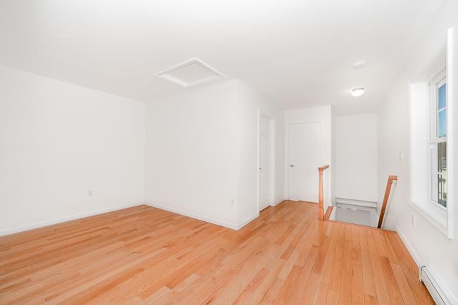 Empty room featuring baseboards, light wood-style flooring, baseboard heating, and attic access | Image 20
