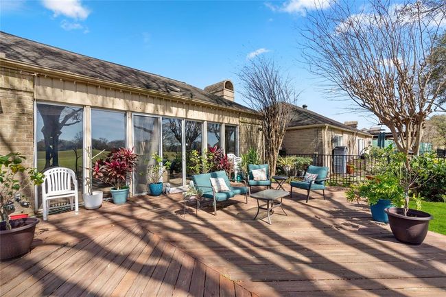 The spacious wooden deck extends from the home, providing a seamless indoor-outdoor connection with large sliding glass doors. Surrounded by mature trees and lush greenery, this outdoor retreat offers a peaceful and inviting atmosphere. The open layout allows for flexible use, perfect for entertaining or enjoying the tranquil golf course views. | Image 35