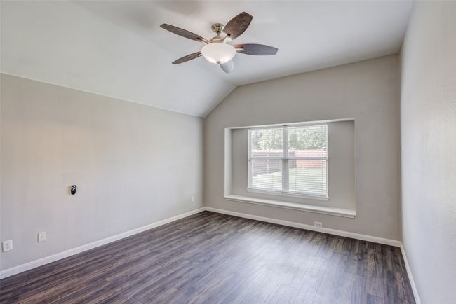 Spare room with a ceiling fan, dark wood finished floors, vaulted ceiling, and baseboards | Image 15