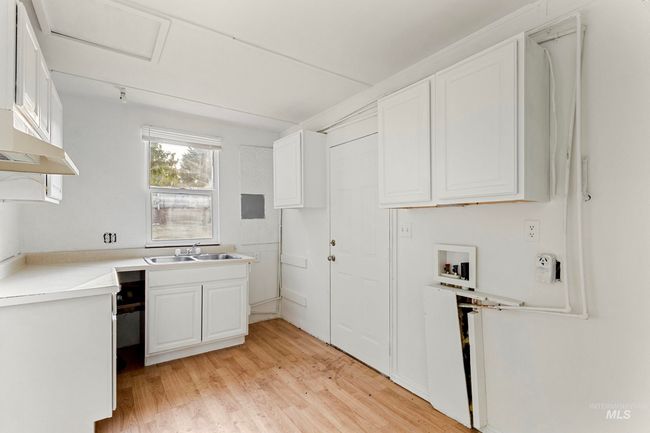 Kitchen with light wood finished floors, white cabinets, light countertops, and wall chimney range hood | Image 20