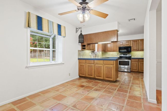 Kitchen featuring stainless steel range with electric cooktop, black microwave, tasteful backsplash, brown cabinetry, and a peninsula | Image 11