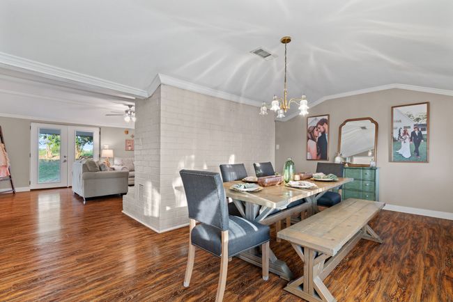 Dining room with crown molding, a chandelier, wood finished floors, and a ceiling fan | Image 6