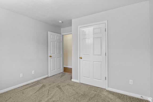 Unfurnished bedroom featuring carpet, baseboards, and a textured ceiling | Image 13