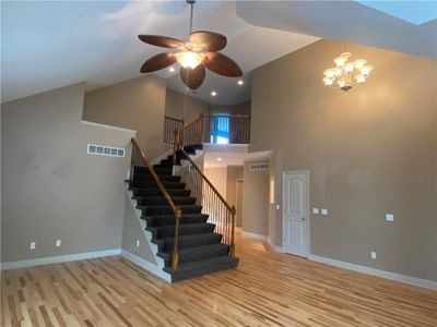 Staircase with a high ceiling, light hardwood / wood-style floors, and ceiling fan with notable chandelier | Image 2