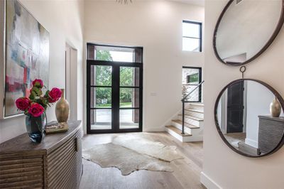 Foyer entrance featuring Pella glass doors, a towering ceiling, and light hardwood floors | Image 1