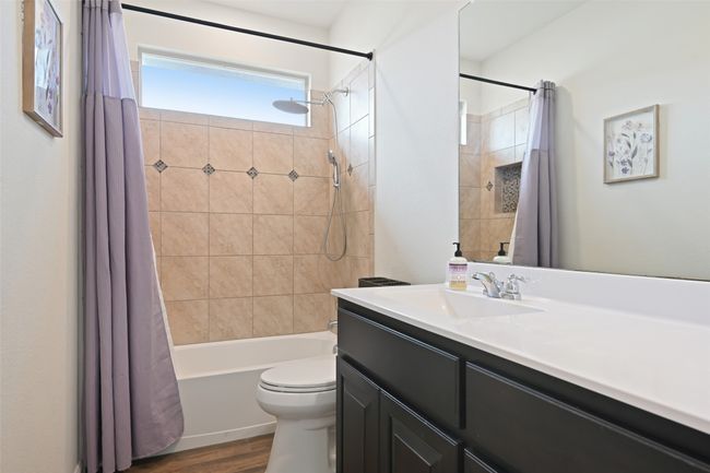 Bathroom with vanity, wood finished floors, shower / bathtub combination with curtain, and toilet | Image 23