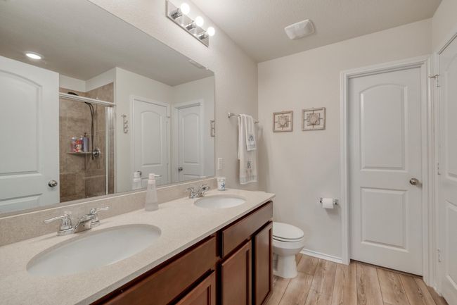 Full bath featuring double vanity, a sink, a shower stall, and wood finished floors | Image 25