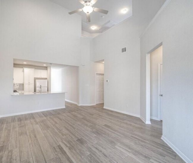 Unfurnished living room with light wood-style flooring, ceiling fan, and a towering ceiling | Image 7