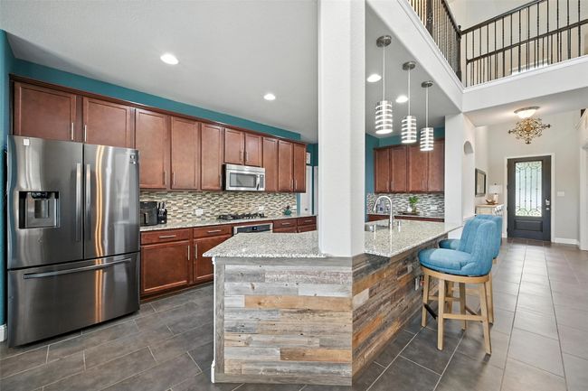 Kitchen featuring stainless steel appliances, dark tile patterned flooring, decorative backsplash, light stone countertops, and recessed lighting | Image 12