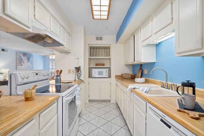 Kitchen featuring white appliances, visible vents, light countertops, and a sink | Image 16