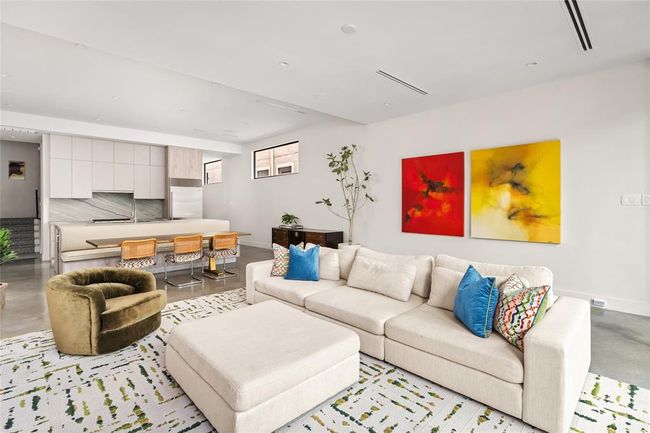 Clean lines and natural light define the first floor’s open-concept living space. Designed for both ease and elegance, the layout features a spacious island with integrated dining area with banquette, and sleek Madeval cabinetry that anchors the minimalist kitchen. Perfect for entertaining or everyday living, the space flows effortlessly from kitchen to living room to outdoor retreat. | Image 8