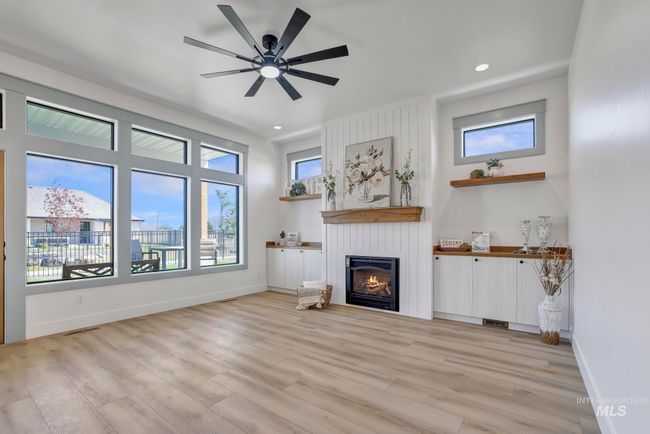 Unfurnished living room featuring a fireplace, light wood-style floors, a ceiling fan, and recessed lighting | Image 6