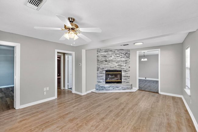 Unfurnished living room featuring light wood-style floors, a ceiling fan, and a stone fireplace | Image 22