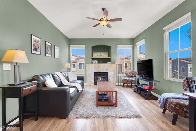 Living room with a ceiling fan, a tiled fireplace, wood like finished floors, and baseboards | Image 10