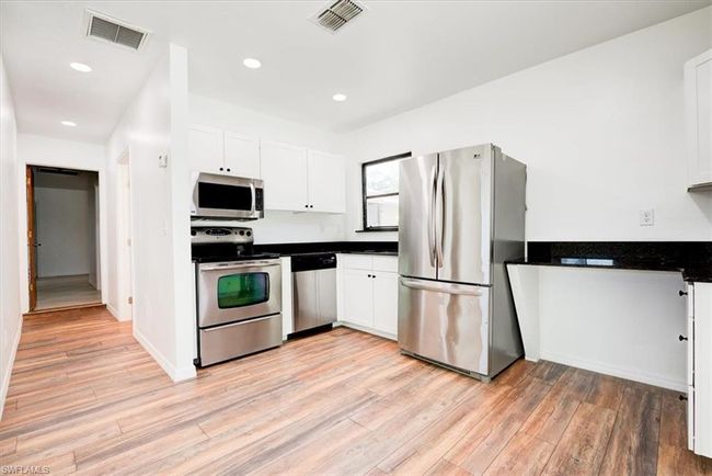 Kitchen with white cabinetry, visible vents, stainless steel appliances, and light wood-style floors | Image 30