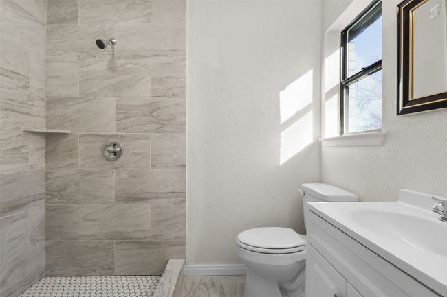 Bathroom featuring tiled shower, vanity, and toilet | Image 13