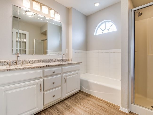 Full bathroom featuring double vanity, wood finished floors, a garden tub, and a shower stall | Image 11