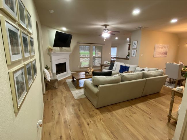 Living area featuring a ceiling fan, a fireplace with raised hearth, luxury vinyl plank wood finished floors, and recessed lighting | Image 11
