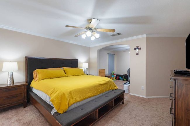 Bedroom with arched walkways, crown molding, light carpet, and ceiling fan | Image 16