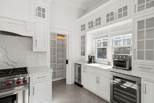 Kitchen featuring white cabinets, sink, decorative backsplash, stainless steel appliances, and beverage cooler | Image 26