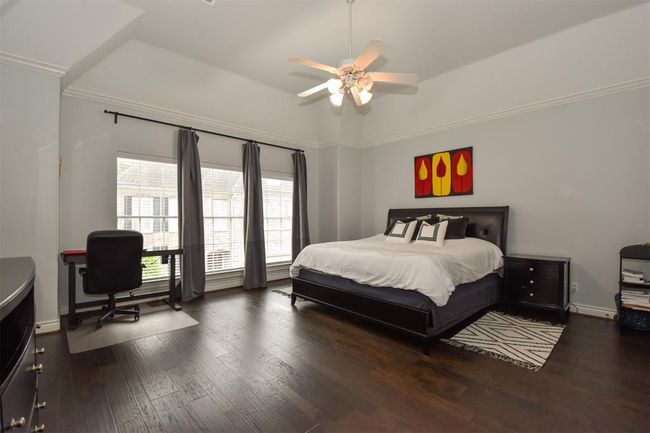 Spacious primary bedroom with hardwood floors, large windows with custom drapes and high ceiling. It has ample space for a work desk and additional furniture | Image 16