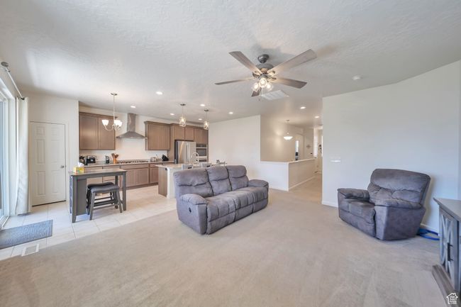 Living area featuring a textured ceiling, ceiling fan, light colored carpet, baseboards, and recessed lighting | Image 7