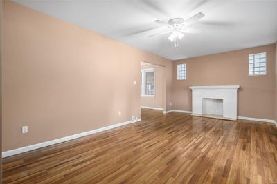 Unfurnished living room featuring ceiling fan, wood-type flooring, and a fireplace | Image 3