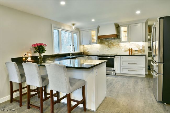 Kitchen with tasteful backsplash, a peninsula, a sink, stainless steel appliances, and custom range hood | Image 14
