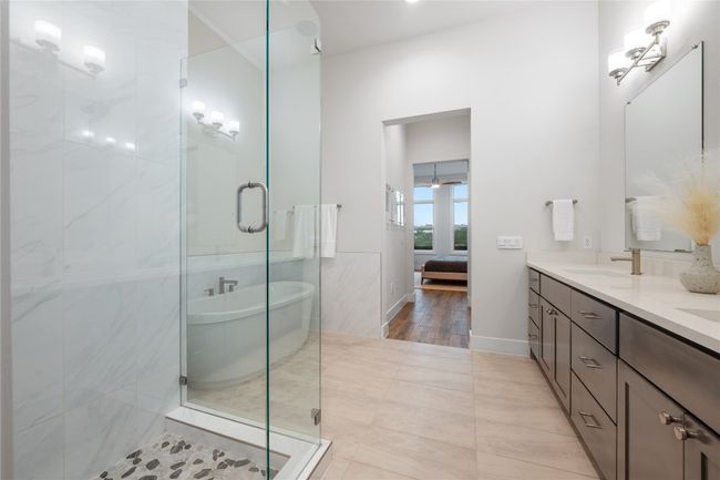 Elegant ensuite oversized primary bathroom features quartz countertops, dual vanity, soaking tub, walk-in shower and walk-in closet. | Image 14