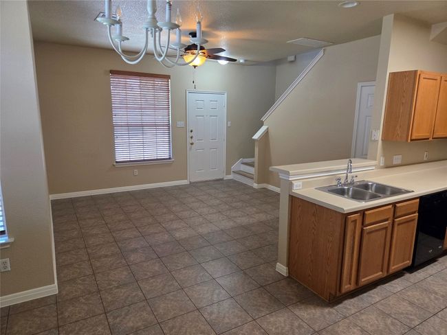 Kitchen featuring black dishwasher, light countertops, ceiling fan, a chandelier, and brown cabinetry | Image 10