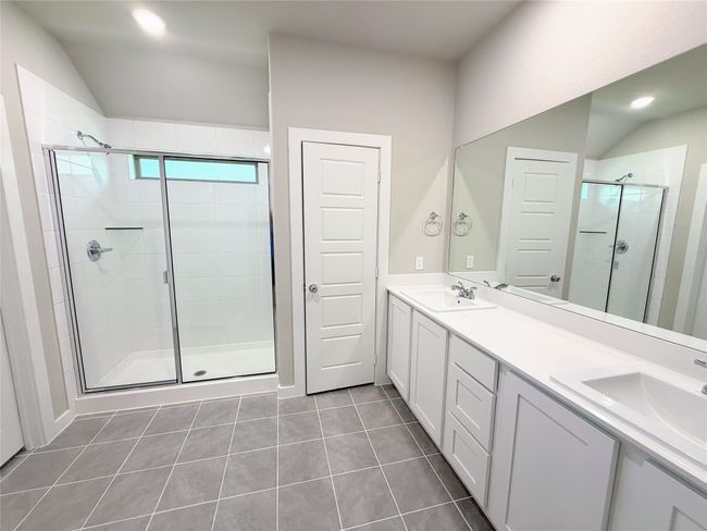 Full bath featuring a stall shower, double vanity, lofted ceiling, tile patterned flooring, and recessed lighting | Image 16