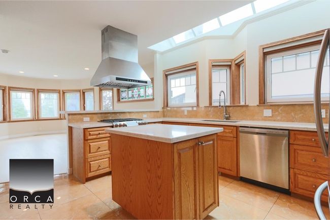Kitchen featuring appliances with stainless steel finishes, island range hood, a kitchen island, a skylight, and plenty of natural light | Image 10