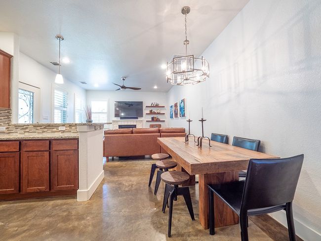 Dining area with concrete floors, ceiling fan, a chandelier, a fireplace, and recessed lighting | Image 10