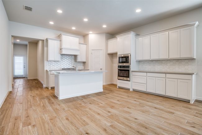 Kitchen featuring stainless steel oven, built in microwave, backsplash, light wood-type flooring, and recessed lighting | Image 6