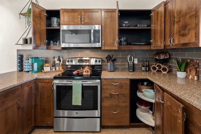 Kitchen featuring open shelves, appliances with stainless steel finishes, stone countertops, and tasteful backsplash | Image 26