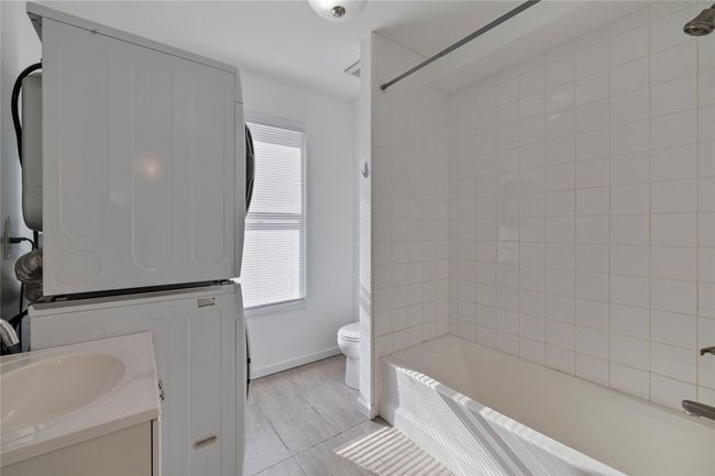 Full bathroom with toilet, a wealth of natural light, shower / tub combination, and stacked washer and dryer | Image 17