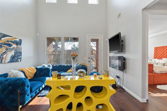 Living room featuring baseboards, a high ceiling, wood-type flooring, and visible vents | Image 4