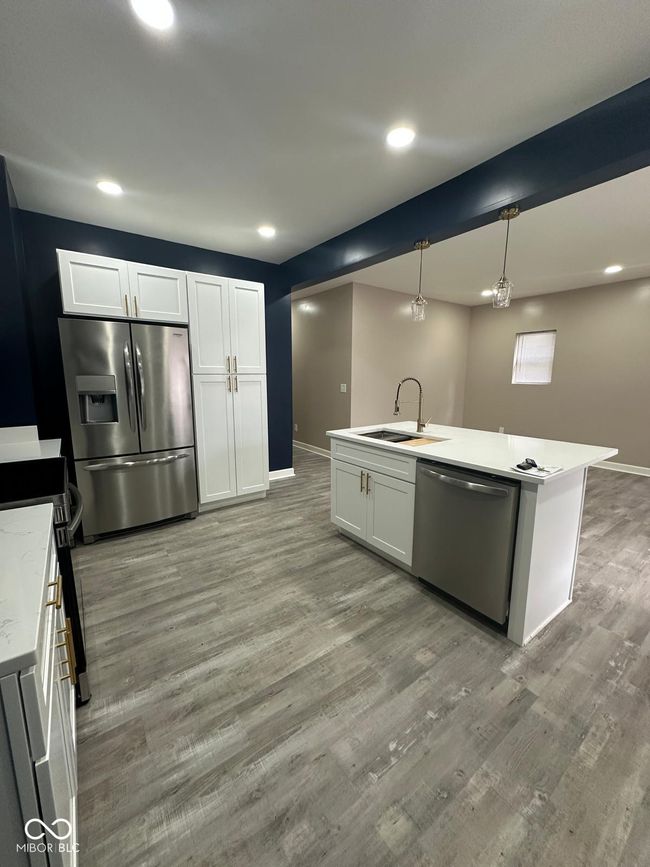 Unit 1 - kitchen featuring stainless steel appliances, light wood finished floors, recessed lighting, light countertops, and hanging light fixtures | Image 7