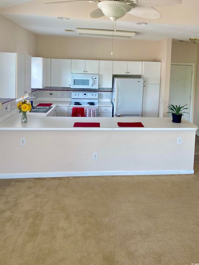 Kitchen with light countertops, visible vents, white appliances, white cabinetry, and a sink | Image 9