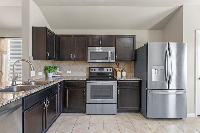 The kitchen features granite countertops and stainless steel appliances. | Image 7