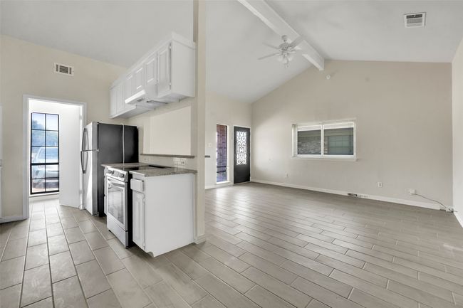 Kitchen featuring stainless steel appliances, ceiling fan, beamed ceiling, white cabinetry, and open floor plan | Image 6