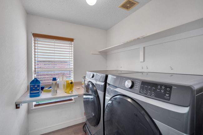 Laundry area with washing machine and clothes dryer, wood finished floors, and a textured ceiling | Image 18