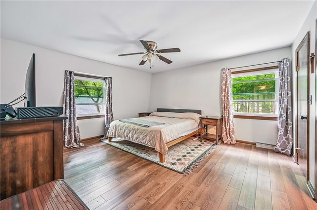 2nd floor Spacious primary bedroom with hardwood floors, a ceiling fan, and ample natural light from two windows. | Image 27
