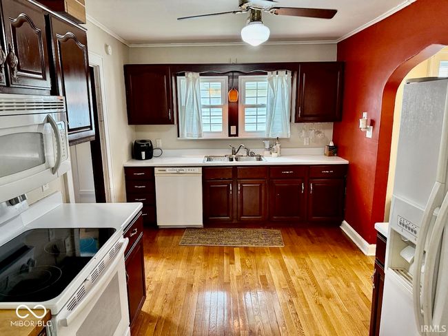 kitchen with white appliances, arched walkways, light wood finished floors, ceiling fan, and light countertops | Image 18