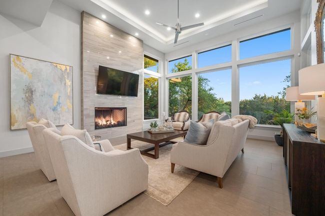 Living area with ceiling fan, a tray ceiling, recessed lighting, a high ceiling, and a high end fireplace | Image 5