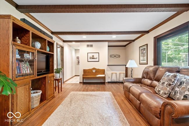 living area with beam ceiling, light wood-style floors, crown molding, and recessed lighting | Image 9