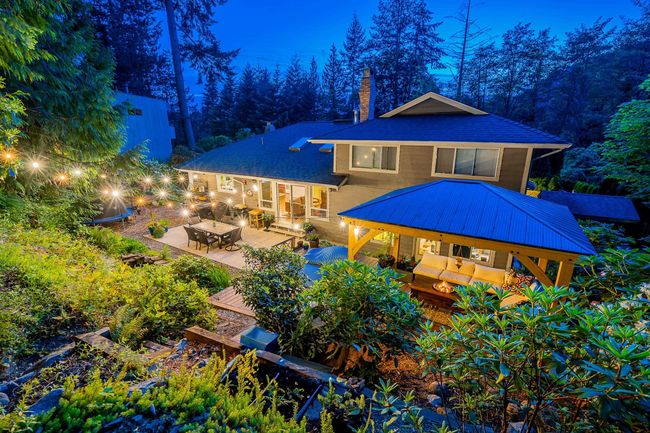 Rear view of house featuring a gazebo, a chimney, a patio area, a metal roof, and an outdoor living space with a fire pit | Image 25
