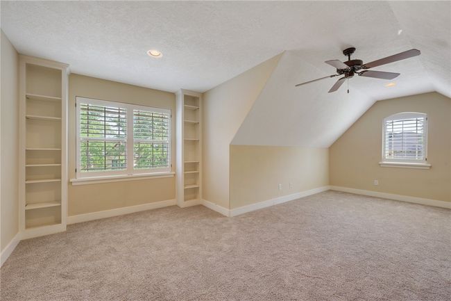 Additional living space featuring a textured ceiling, carpet, baseboards, ceiling fan, and vaulted ceiling | Image 14